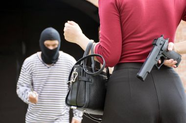 Male robber standing and looking at young woman and young woman hide gun in his back clipart
