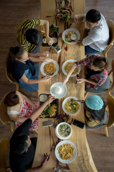 Enjoying dinner with friends. Top view of group of people having dinner together while sitting at the rustic wooden table