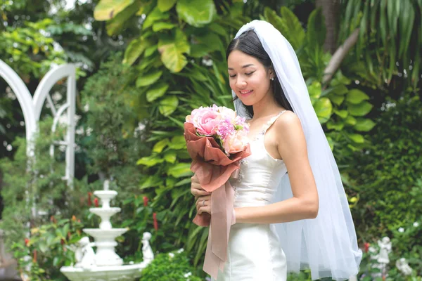 Νύφη σε ένα λευκό φόρεμα, κρατώντας την ανθοδέσμη γάμου με κορδέλες — Φωτογραφία Αρχείου