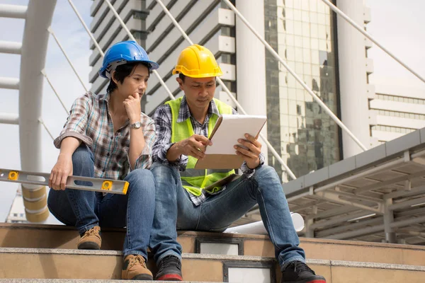 Due ingegneri edili che lavorano all'aperto, discutendo della costruzione in cantiere — Foto Stock