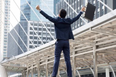 Evrak Çantası'nı tutarak ve yetiştirme Asya iş adamı ayakta iş başarı için merkezinde silah