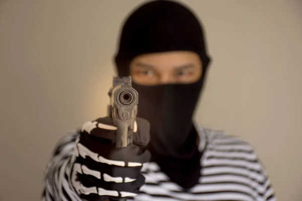 The terrorists aiming his weapon under the mask with the blurry face behind,criminal concept
