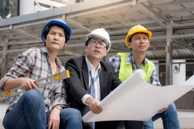 Takım mühendisleri ve açık havada çalışan, proje planları ile tartışırken ustabaşı.