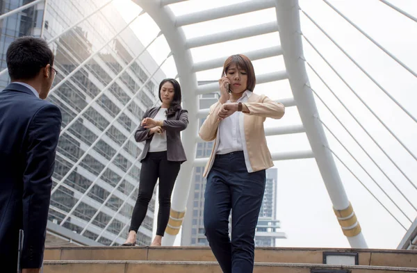 Ve acele modern bir geçit üzerinde yürüyen kol saati görünümlü cep telefonu tutarak Asya iş adamları