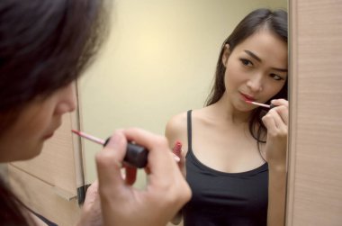 Portre portre ayna, güzel Asyalı bir kadın kırmızı ruj dudakları boyalar