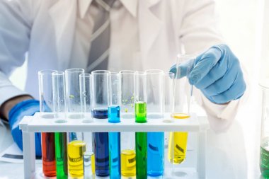 Laboratuvarda bir sıvı kimyasal çözüm ile sarı tüp tutan bilim adamı kimyacı