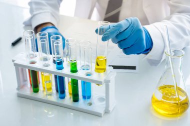 Laboratuvarda bir sıvı kimyasal çözüm ile sarı tüp tutan bilim adamı biyoloji kimyager