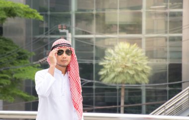 Sıcak bir günde şehirde yürüyüş güneş gözlüğü takıyor Arapça yakışıklı adam