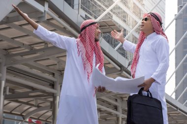 İki Arap işadamı buluşup birlikte konuşurken evrak çantası şehir arka plan/iş kavramı ile tutarak tartışmıyoruz bilgi formları. 