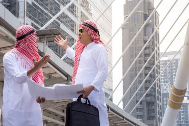 İki Arap işadamı buluşup birlikte konuşurken evrak çantası şehir arka plan/iş kavramı ile tutarak tartışmıyoruz bilgi formları. 