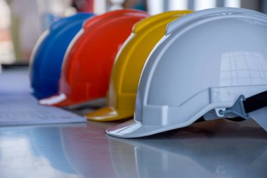 Kavramın mimarı, mühendisi ya da işçi daralma ekipman/Emanet işbirliği çalışmalarında güvenliği projesi için masaya Blueprint ve beyaz, mavi, kırmızı ve sarı zor emanet kask şapka