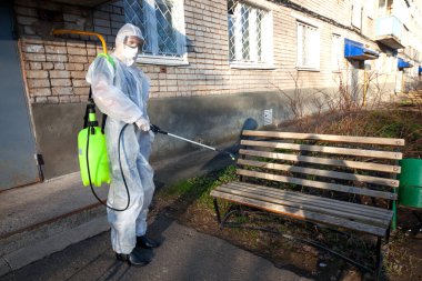 Disinfection of a bench in the courtyard of an apartment building. Fight against viruses, infections, insects, mice clipart