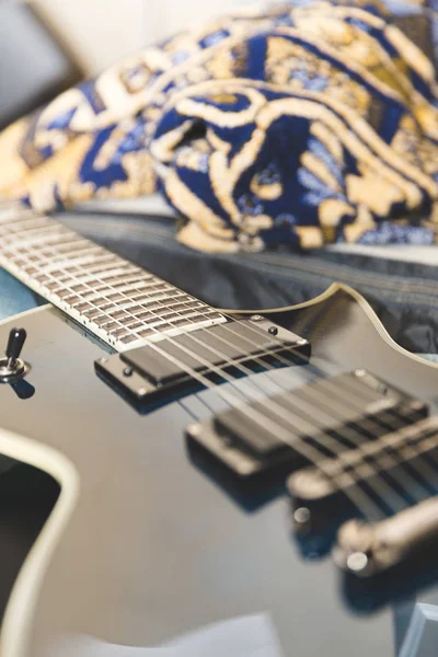 Guitarra elétrica azul e preta em uma cama . — Fotografia de Stock