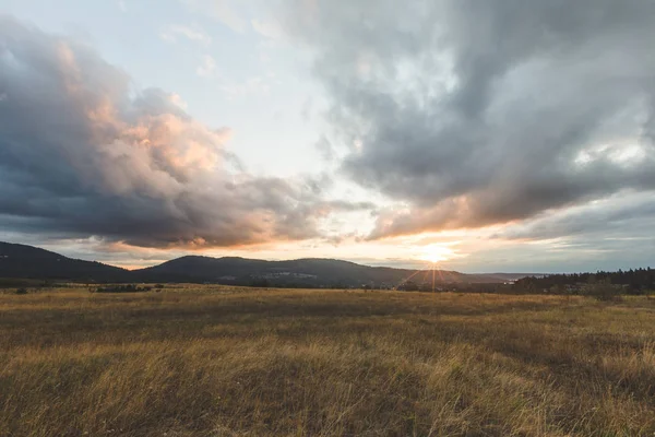 Nublado atardecer sobre montañas y campo — Foto de Stock