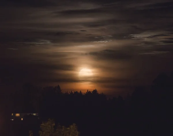 Lune dans un ciel nuageux au-dessus des arbres — Photo