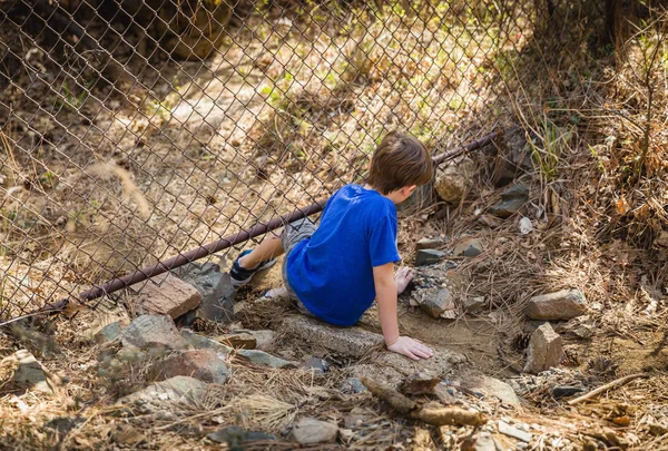 Young Boy Climbing Under Fence — Stock Photo, Image