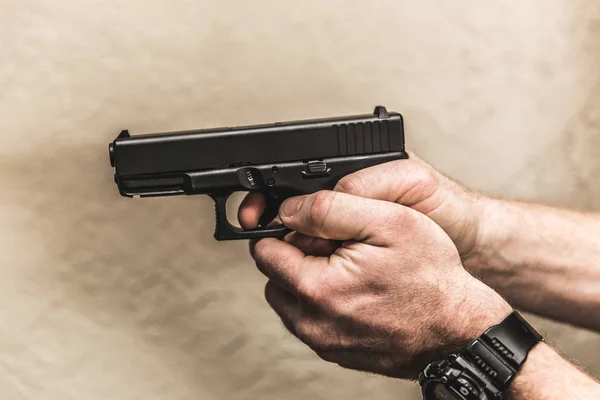 Mãos segurando arma com o dedo no gatilho — Fotografia de Stock