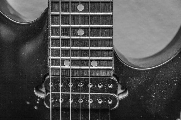 Dusty details of a 7-string electric guitar showing the strings and fret board.