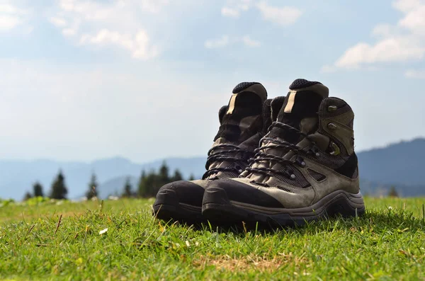 Botas de senderismo en la hierba y las montañas de fondo — Foto de Stock