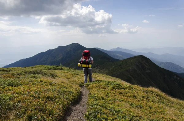 Turista con una mochila en las montañas — Foto de Stock