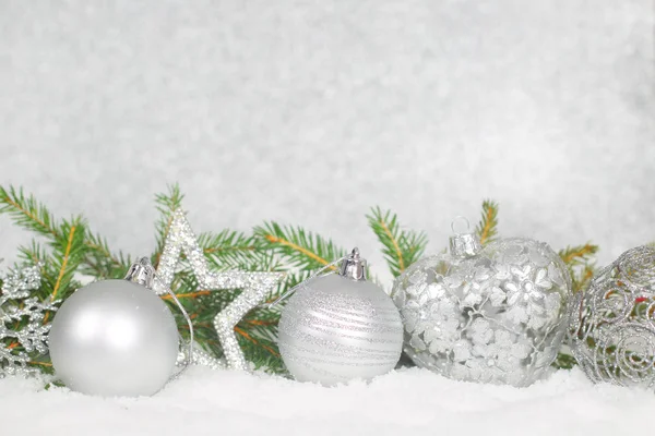 Weihnachtskugeln und grüner Tannenzweig auf Schnee — Stockfoto