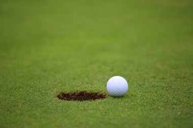 Golf ball on lip of cup