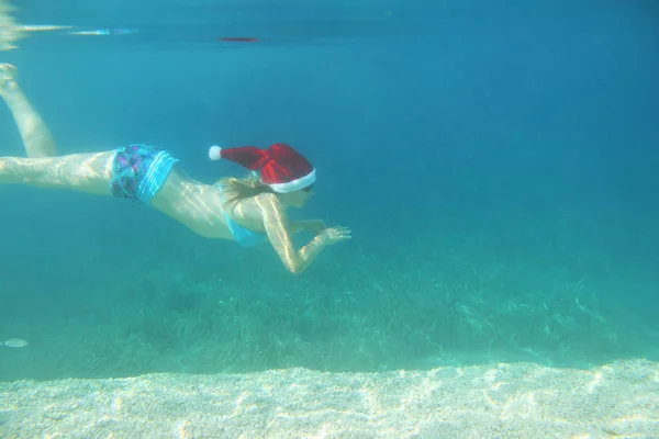 Vrouw in Santa hat onderwater zwemmen — Stockfoto