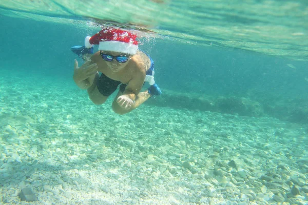 Αγόρι στο καπέλο Santa κολύμπι στη θάλασσα — Φωτογραφία Αρχείου