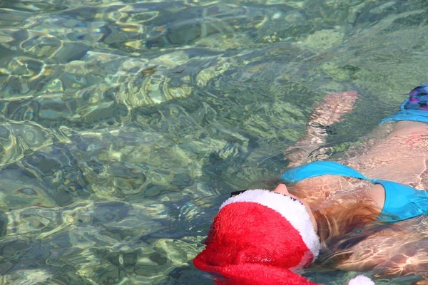 Γυναίκα με καπέλο Santa κολύμπι στη θάλασσα — Φωτογραφία Αρχείου