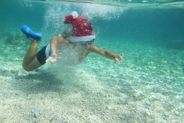 Pojke i Santa hatt simning i havet — Stockfoto