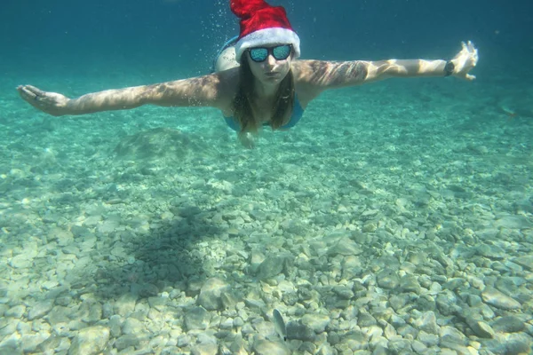 Жінка в Санта hat плаванням під водою — стокове фото
