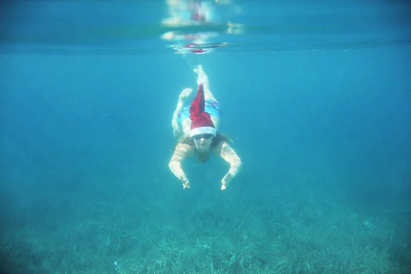 Nő a Santa kalap víz alatti úszás — Stock Fotó