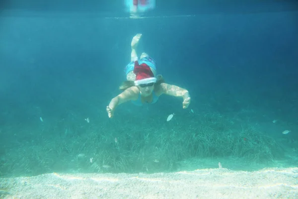 Kvinna i Santa hatt simma under vattnet — Stockfoto