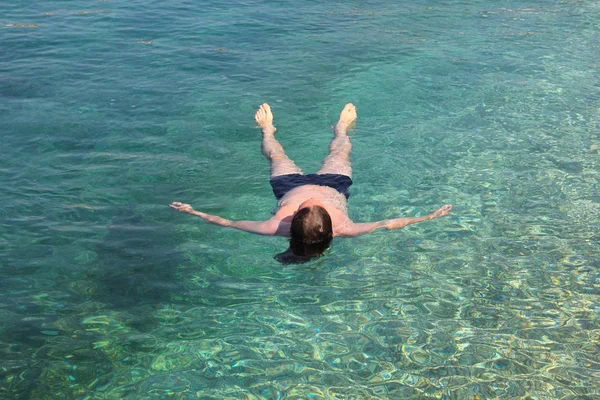 Homem flutuando na água do mar — Fotografia de Stock