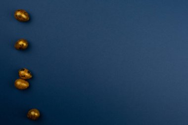 Mavi arkaplan üzerinde küçük altın bıldırcın paskalya yumurtaları metin için kopyalama alanı