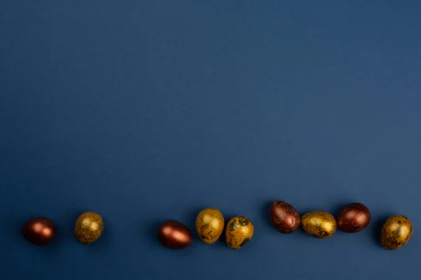 Huevos Pascua Codorniz Dorada Pequeños Una Fila Sobre Fondo Azul —  Fotos de Stock