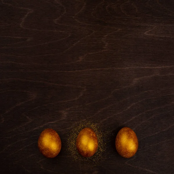 Tres Grandes Huevos Pascua Dorados Sobre Fondo Madera Oscura Espacio —  Fotos de Stock