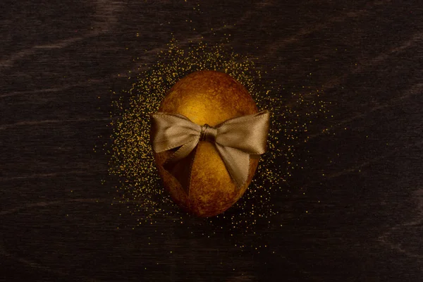 Ein Großes Goldenes Osterei Mit Schleife Auf Dunklem Holzhintergrund Kopiert — Stockfoto