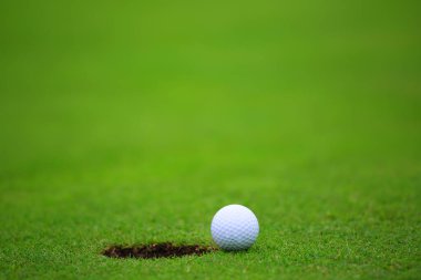 Deliğe yakın golf topu, fincanın dudağında golf sahası arka planında metin pankartı için fotokopi alanı