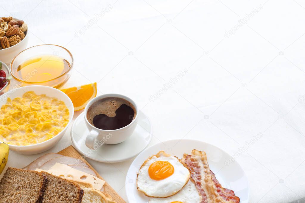 Healthy breakfast with muesli, fruits, berries, nuts, coffee, eggs, honey, oat grains and other on white background. Flat lay, top view, copy space for text, frame