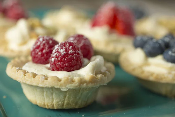 Tartlets with berries in a green plate — Stock Photo, Image