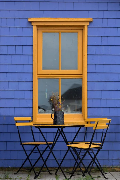 Yellow patio table with purple wall — Stock Photo, Image