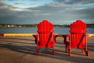 Kırmızı adirondack sandalyeler önünde su