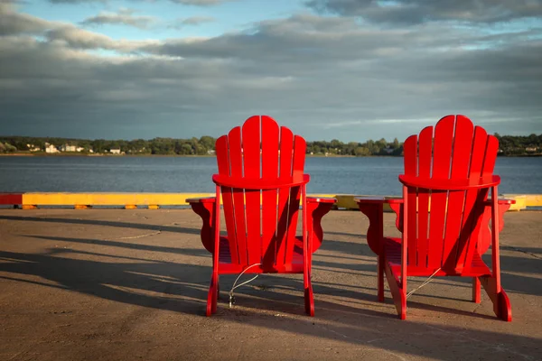 Red adirondack chairs in front of water — Stock Photo, Image