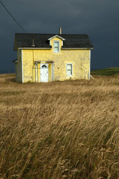 Žlutý dům s tmavě šedou oblohu — Stock fotografie