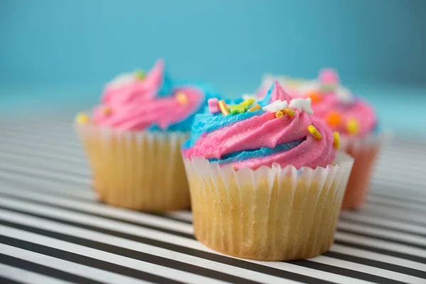 Cupcakes με μπλε και ροζ γαρνιτούρα σε μπλε φόντο — Φωτογραφία Αρχείου