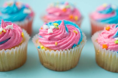 Mavi arka planda mavi ve pembe kremalı kekler.