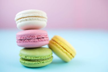 Pembe, sarı, beyaz ve yeşil geleneksel Fransız kurabiyeleri pembe ve mavi arka planda.