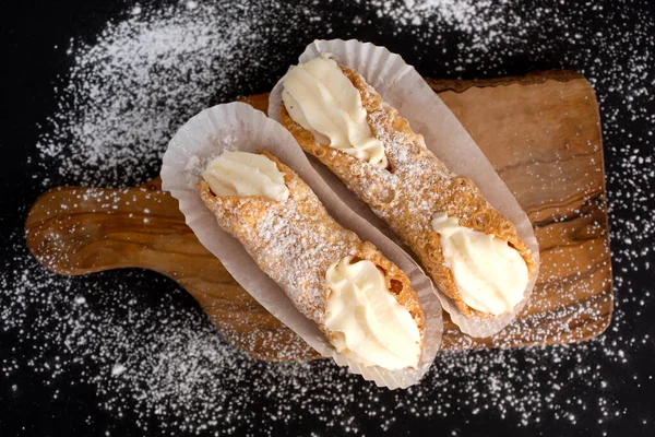 Horní Pohled Dva Čerstvé Cannoli Papíře Skříni Černém Pozadí Prášku — Stock fotografie