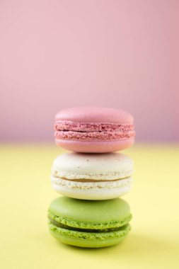 Pembe, beyaz ve yeşil geleneksel Fransız kurabiyeleri pembe ve sarı arka planda.